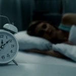 Woman sleeping in bed in dark bedroom