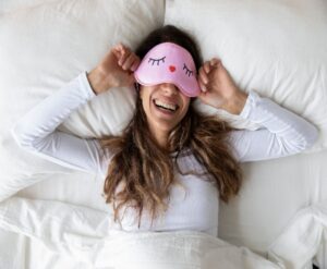 Woman wearing a sleep mask thinking positive thoughts before bed - Simply Good Sleep