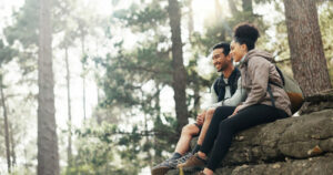 A man and a woman relaxed, smiling, appreciating the wonder and beauty of the forest - in Forest Bathing - A Natural Remedy for Better Sleep - Simply Good Sleep